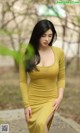 A woman in a yellow dress posing for a picture.