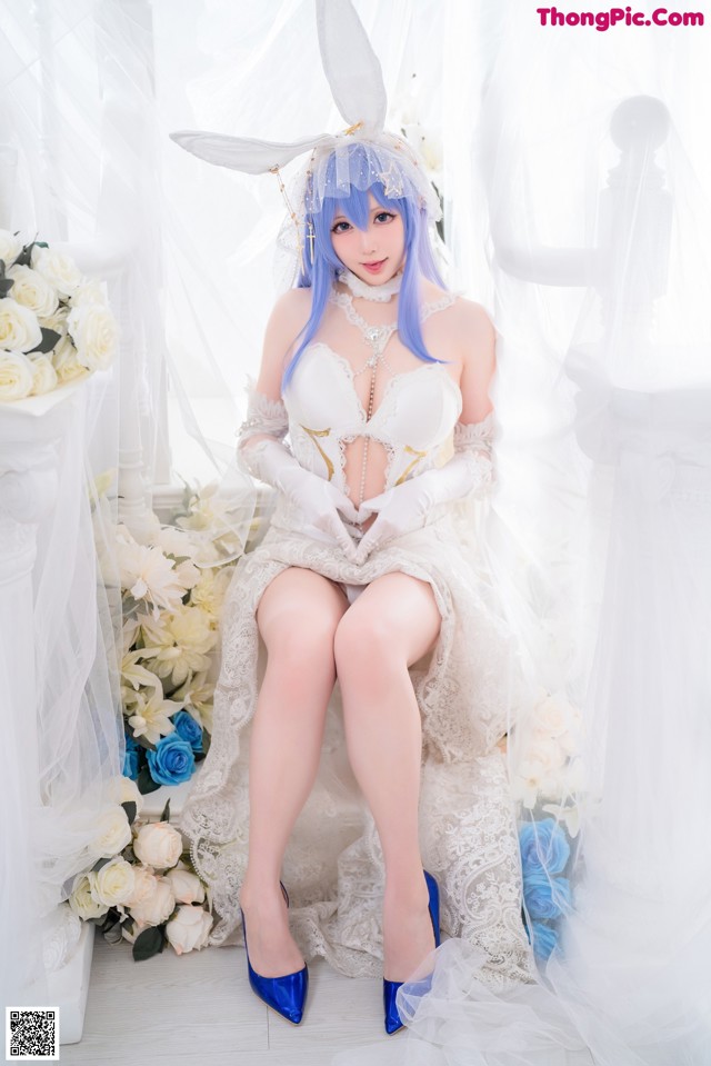 A woman in a white dress sitting on a bed of flowers.