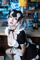 A woman dressed as a maid sitting at a bar.