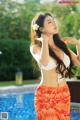 A woman in a bikini standing next to a swimming pool.