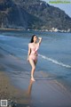 A woman in a pink bikini standing on a beach.