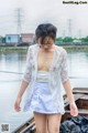 A woman in a white top and blue skirt standing on a dock.