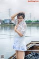 A woman in a white top and blue skirt posing on a boat.