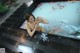 A naked woman sitting in a bathtub filled with rose petals.