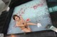 A naked woman sitting in a bathtub filled with water and rose petals.