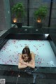 A woman laying in a bathtub filled with rose petals.