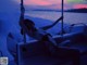 A woman in a bikini sitting on a boat in the water.