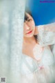 A woman in a white lingerie leaning against a curtain.