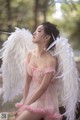 A woman in a pink dress with white angel wings.