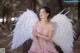 A woman in a pink dress with white angel wings.