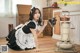 A woman in a maid outfit cleaning the floor with a broom.