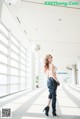 A woman in a white top and black pants standing in an airport.