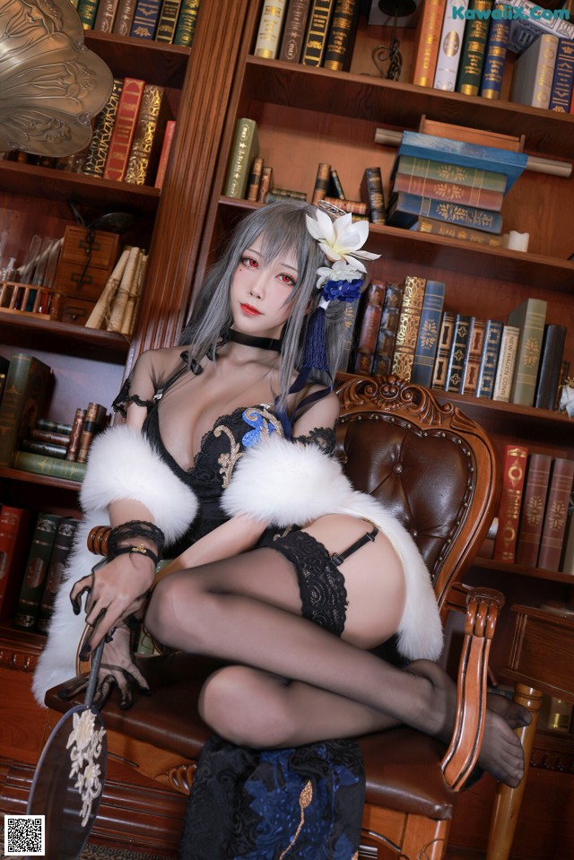 A woman sitting on a chair in front of a bookcase.