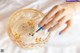 A woman's hand holding a paintbrush in a glass bowl.