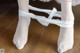 A close up of a person wearing white stockings on a wooden floor.