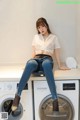 A woman sitting on top of a washing machine.