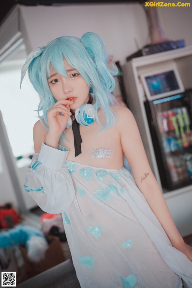 A woman with blue hair wearing a white dress and headphones.