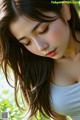 A woman with long brown hair and a white tank top.