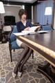 A woman sitting at a table with a book in her hand.