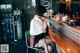 A woman sitting at a bar smoking a cigarette.