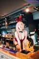 A woman in a bunny costume sitting at a bar.