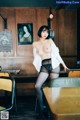 A woman in black stockings and a white shirt posing in a restaurant.