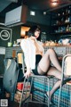 A woman sitting on a bar stool in a restaurant.