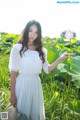 A woman in a white dress standing in a field of flowers.