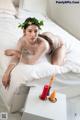 A woman laying on a bed with a flower crown on her head.